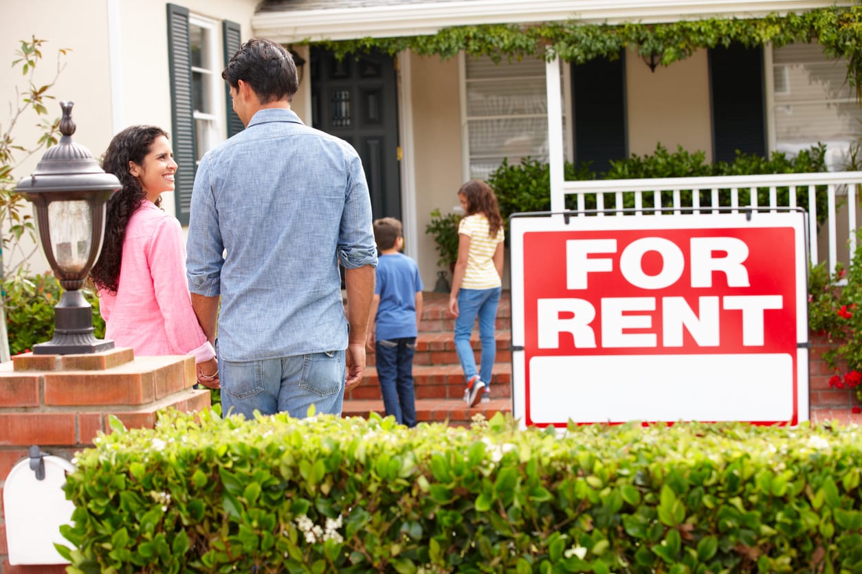 Happy Family Walking into Suburban Home with For Rent Sign in Yard